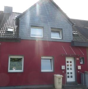 ein rotes Haus mit einem Hund im Fenster in der Unterkunft Flughafenapartement Sky View in Düsseldorf