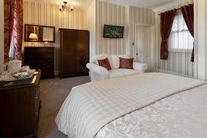 a bedroom with a large white bed and a chair at Beechwood in Bowness-on-Windermere +25 photos