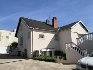 a white house with a staircase in a parking lot at Maison d Eloise in Sartrouville