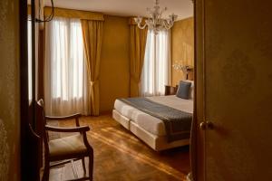 a hotel room with a bed and a chair at Hotel Pensione Wildner in Venice
