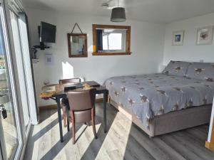 a bedroom with a bed and a desk and a table with a chair at Lampay Chalets in Dunvegan