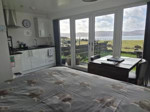 a kitchen with a bed and a desk with a window at Lampay Chalets in Dunvegan