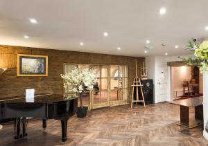 a living room with a black piano and wooden floors at Santo's Higham Farm Hotel in Alfreton