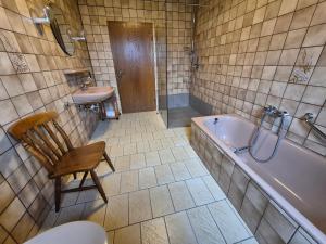 a bathroom with a tub and a chair and a sink at Ferienwohnung Marx in Konz