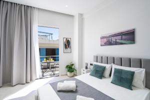 a white bedroom with a bed and a balcony at Notos Horizon in Ierapetra