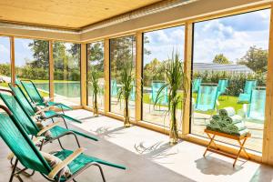 a screened porch with green chairs and windows at Golfresort Haugschlag in Haugschlag