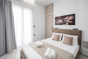 a white bedroom with a large bed with two white towels at Notos Horizon in Ierapetra