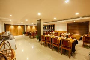 a restaurant with tables and chairs in a room at Hotel Laals Inn Grand in Cochin