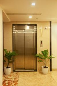 two potted plants in front of a elevator at Hotel Laals Inn Grand in Cochin