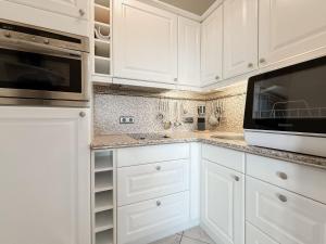 a white kitchen with white cabinets and a microwave at Carpe Diem 203 in Niendorf