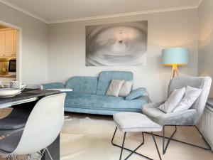 a living room with a blue couch and chairs at Carpe Diem 203 in Niendorf