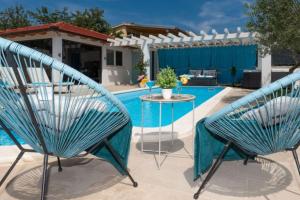 two chairs and a table next to a swimming pool at Villa Korana with heated Pool & Jacuzzi in Kamenmost