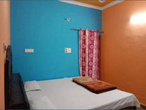 a bedroom with a bed with a blue wall at Green Valley Homestay in Barkot