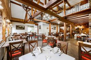 a restaurant with white tables and chairs and wooden ceilings at Hotel Młyn Aqua Spa in Elblag