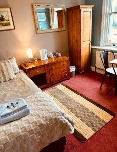 a bedroom with a bed and a dresser and a table at The Lincoln Arms Pub & Rooms in Dorking