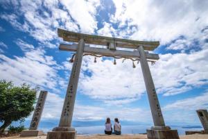 Zwei Personen stehen vor einem großen Felsen am Strand in der Unterkunft HOTEL MYTH-W -ホテル マイス ダブリュー- adult only in Sakaide