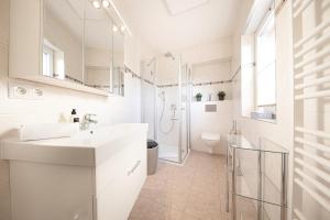 a white bathroom with a sink and a shower at Ferienhaus Coordtino in Putbus
