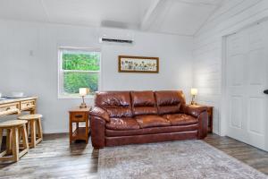 a brown leather couch in a living room with a window at Tiny House on the Hill in New Braunfels