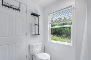 a white bathroom with a toilet and a window at Tiny House on the Hill in New Braunfels