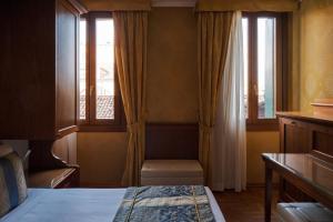 a bedroom with two windows and a bed and a table at Hotel Pensione Wildner in Venice +12 photos