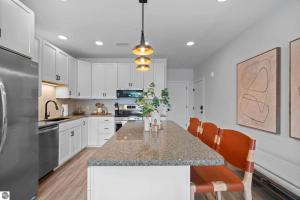 a kitchen with white cabinets and a kitchen island with chairs at 1 Block to Beach | Bikes, Wellness & More in Traverse City