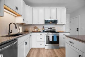 a kitchen with white cabinets and stainless steel appliances at 1 Block to Beach | Bikes, Wellness & More in Traverse City