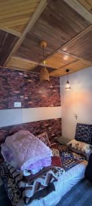 a bed in a room with a brick wall at Scenic Mountain Hut Naranag in Kangan
