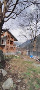 a house being constructed in a yard with a tree at Scenic Mountain Hut Naranag in Kangan