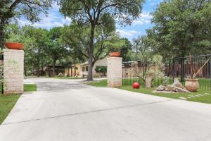 a driveway with two pillars and a fence at Three Sisters - Casita 2 in Wimberley