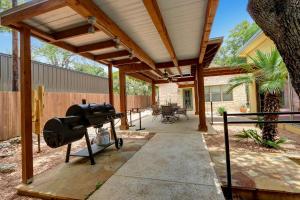 a wooden pergola with a grill on a patio at Three Sisters - Casita 1 in Wimberley