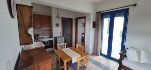 a kitchen and dining room with a table and chairs and a kitchen with a door at Villa Avra - Apartment Hydra in Asgourou