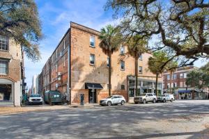 a city street with cars parked in front of a brick building at Above Broughton St 3002 in Savannah