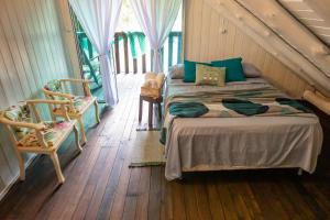 a bedroom with a bed and two chairs at Sítio Temporada in Guabiruba