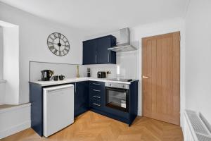 a kitchen with blue cabinets and a clock on the wall at Seaside Snug in Largs