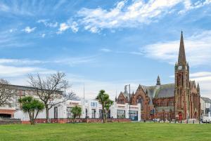 a large church with a clock tower in a field at Seaside Snug in Largs