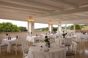 a banquet hall with white tables and chairs and windows at Masseria Bandino & Spa in Otranto
