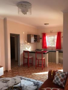 a living room with a kitchen with red curtains at Kristina Gardens in Voi