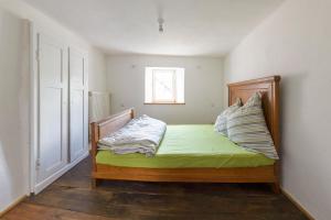 a bedroom with a bed with green sheets and a window at Nengshof Ferienhaus Gänseblümchen in Wißmannsdorf