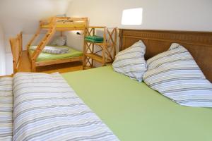 a bed with striped pillows and a bunk bed with a ladder at Nengshof Ferienhaus Gänseblümchen in Wißmannsdorf