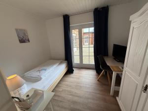 a small room with a bed and a desk and a window at Landhotel Franck Garni in Brietlingen