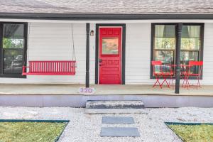 a white house with a red door and red chairs at The Tilted Texan in Buda