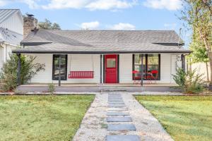 a white house with a red door and a yard at The Tilted Texan in Buda