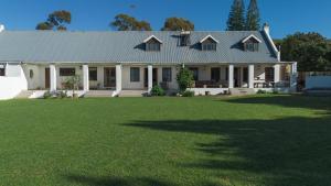 a white house with a large lawn in front of it at Brummer House - Living The Breede in Malgas