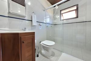 a bathroom with a toilet and a sink and a window at Casa Morrinhos 17 in Garopaba +26 photos