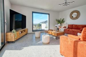 a living room with a couch and a flat screen tv at BELLEVUE 1, piscine, jacuzzi, sauna in Champcevinel