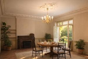 a dining room with a table and a chandelier at Chez ma poule in Moissac