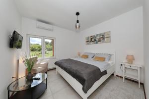 a white bedroom with a bed and a glass table at Villa Demare with Heated Pool, Free EVC Station in Lovinac