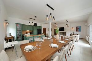 a dining room and kitchen with a large wooden table and chairs at Villa Demare with Heated Pool, Free EVC Station in Lovinac