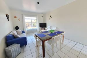 a living room with a table and a blue couch at Condomínio Villa do Oceano in Garopaba