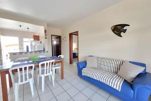 a living room with a blue couch and a table at Condomínio Villa do Oceano in Garopaba